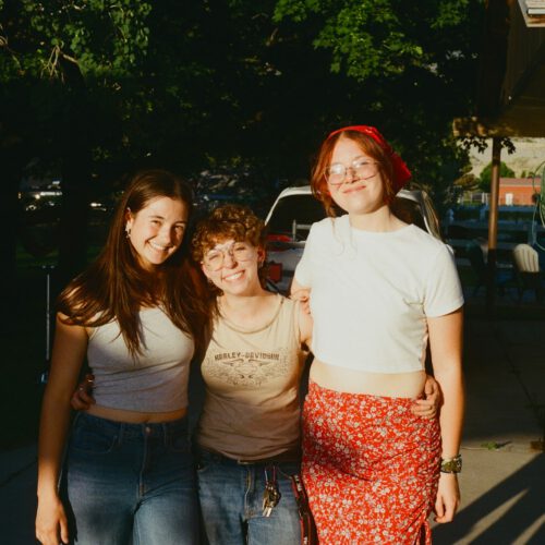 Three smiling friends pose for a photo together.